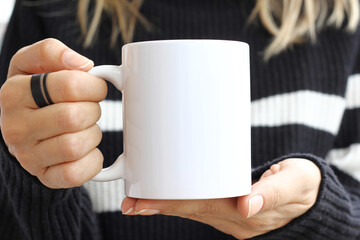 Girl is holding white cup in hands. 11 oz mug in woman's hands.