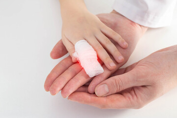 The hands of the doctor bandage the sore finger with a bandage of the child. Injury and wound on...