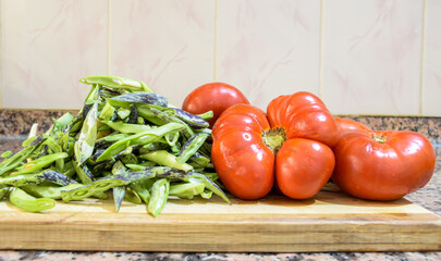 green beans and organic tomatoes on chopping board in kitchen