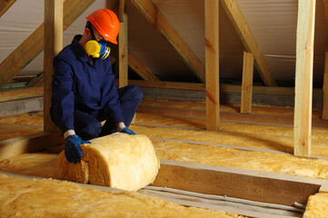 Man installing thermal insulation layer under the roof