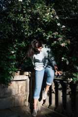 Happy smiling brunette woman hide in shadows of blossoming branch.