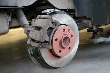 A new brake disc is installed on the car. The brake caliper is corroded. Selected focus. - obrazy, fototapety, plakaty