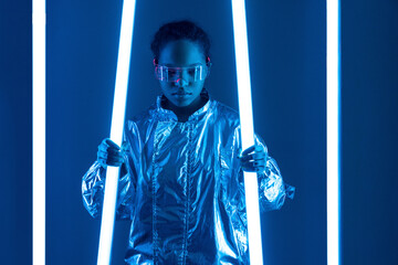 Woman in smart glasses holding illuminated neon light against blue background