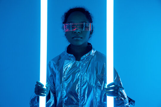 Woman holding illuminated neon lights against blue background