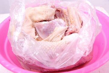 closeup, pile of chicken pieces in a pink bowl. plain white isolated