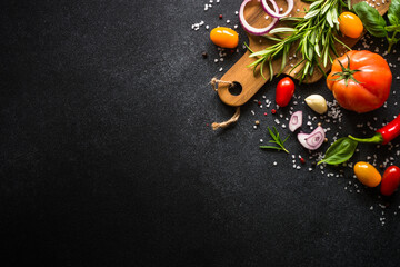 Food cooking background on black stone table. Fresh vegetables, herbs and spices. Top view with...