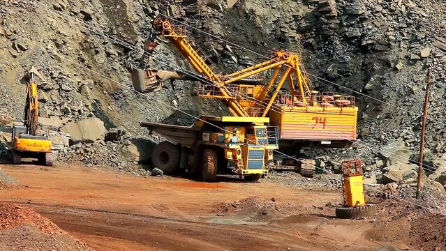 An excavator in a quarry loads soil into a dump truck. The process of mining iron ore in a quarry. Equipment for the extraction of iron ore in an open pit. The smart process in an iron ore quarry