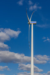 Turbina wiatrowa z profilu na tle chmur w słoneczny dzień