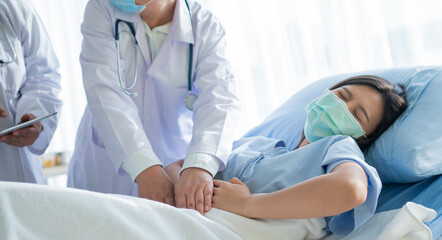 Group of Doctor try to help patient woman lie on hospital bed and holding on stomach suffering. Abdominal pain that comes from menstruation, diarrhea, or indigestion. Sickness and healthcare concept