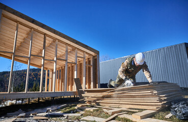 Carpenter using circular saw for cutting wooden OSB board. Man worker building wooden frame house...