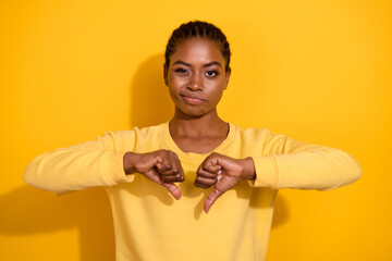 Fototapeta Portrait of attractive skeptic girl showing thumb down dislike no isolated over bright yellow color background obraz
