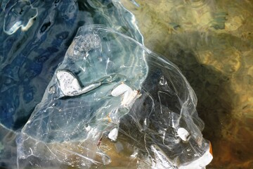 Transparente Folie mit Muster und Wassertropfe in Brunnenwasser mit braunem Untergrund 