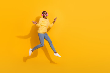 Fototapeta na wymiar Full length body size view of attractive trendy cheerful girl jumping listening pop copy space isolated over bright yellow color background