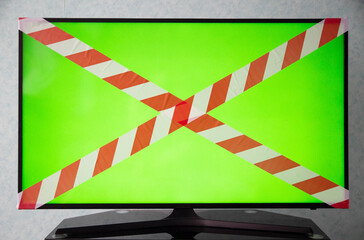 Green TV screen with red and white prohibition tape. The concept of a sanction on television, a ban...