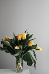 Beautiful yellow tulips in glass vase at home. Colourful spring flowers