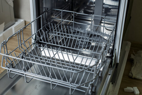 open dishwasher. the hostess is preparing to load dirty dishes into the dishwasher.