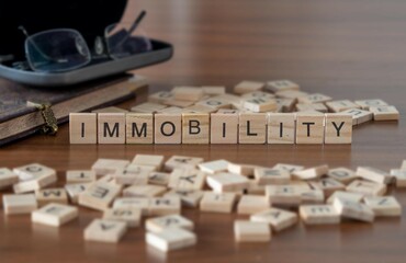 immobility word or concept represented by wooden letter tiles on a wooden table with glasses and a...