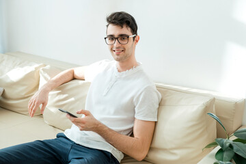Obraz premium Communication and people concept. A young man looks at the camera and smiles, holding a gadget in his hands.
