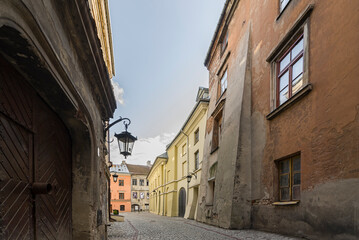 Fototapeta na wymiar Klimatyczna uliczka na Starym Mieście w Lublinie. Stare i nowe kamienice. Wisząca latarnia na ścianie