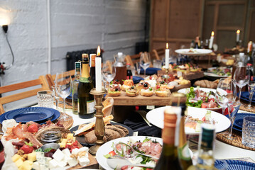 Festive table with delicious appetizers and snacks. Holiday banquet serving with fancy glasses and silverware in restaurant. Wedding birthday party celebration.