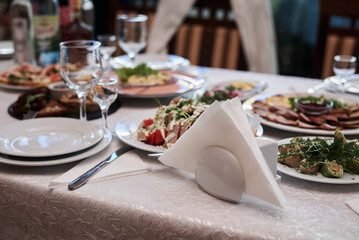 Festive table with delicious appetizers and snacks. Holiday banquet serving with fancy glasses and silverware in restaurant. Wedding birthday party celebration.