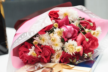 Beautiful flowers bouquet lying on a table. Pink, red, ivory chrysanthemums as a birthday present. Festive decorations for holiday.