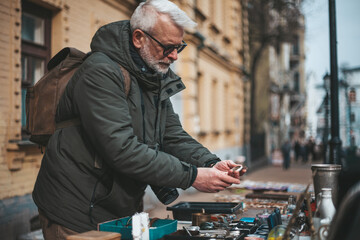 Mature man buys rare collectibles at a flea market. Nostalgia for the past.