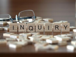 inquiry word or concept represented by wooden letter tiles on a wooden table with glasses and a book