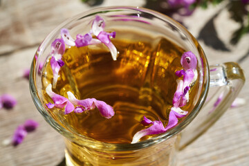 Purple dead-nettle flowers in a cup of herbal tea, closeup