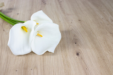 bouquet of three white calla lilies on wooden background
