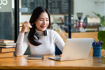 Asian students, girls, sit and read books and do homework on laptops. Make long-distance video calls using an Internet connection with a teacher in a coffee shop.