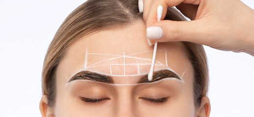 Make-up artist makes markings with white pencil for eyebrow and paints eyebrows. Professional...