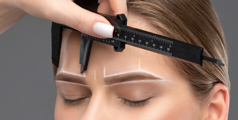 Make-up artist makes markings with white pencil for eyebrow and paints eyebrows. Professional...