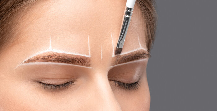 Make-up artist makes markings with white pencil for eyebrow and paints eyebrows. Professional makeup and facial care.