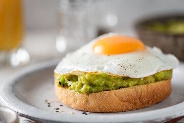 Breakfast english muffin toast with avocado and fried egg, closeup view