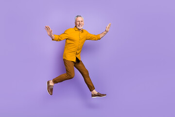 Fototapeta na wymiar Full size photo of excited mature man have fun jump up energetic isolated over purple color background