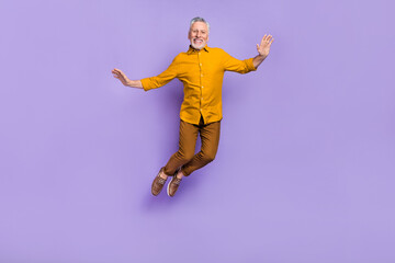 Full body photo of cheerful mature man have fun jump up fly dream isolated over purple color...