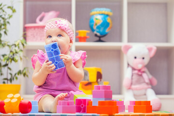 Obraz na płótnie Canvas baby girl playing with colourful building blocks at home or kindergarten