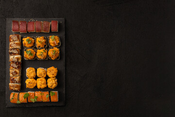 Set of various sushi rolls Japanese food on a black board for serving on a black background