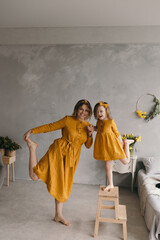 Mom and daughter in linen dresses are spinning, laughing and having fun