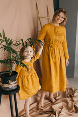 Mom and daughter in linen dresses are spinning, laughing and having fun