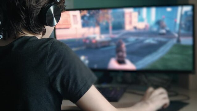 Boy teen play a computer game at home. online video game technology concept. blur boy teen play shooter video game on a mouse with a keyboard. addiction gambling from video games