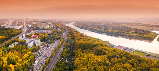 Aerial view of the picturesque autumn river in the suburbs of an industrial city and the transport railway road