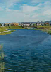 Vertical Whispy white clouds Oquirrh Lake at Daybreak in Utah with paved sidewalk on the side