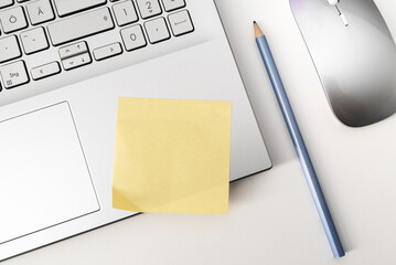 above view of blank yellow sticky note on laptop computer