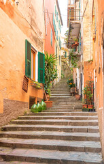 A cute Italian street with numerous steps rises up between the terracotta-colored houses