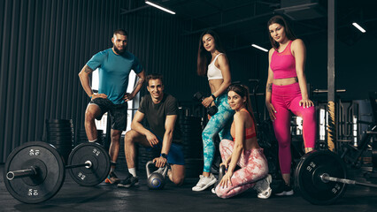 Group of young friends doing sports, training at gym indoors. Sportive youth concept