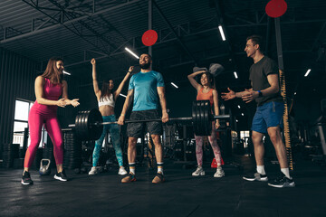 Group of young friends doing sports, training at gym indoors