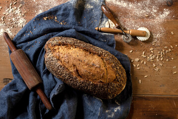 Homemade sourdough bread with seeds in different shapes and styles with olive oil on a still life table with a cloth rolling pin and window light