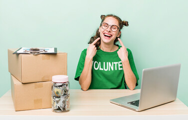 young pretty woman  smiling confidently pointing to own broad smile. donation volunteer concept